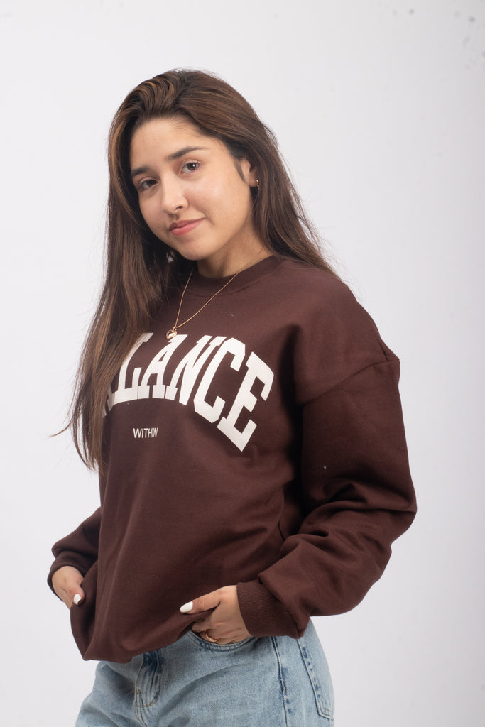 Evocando las raíces urbanas, la polera de franela en marrón se adorna con 'BALANCE', ideal para chicas jóvenes con pasión por la ciudad.