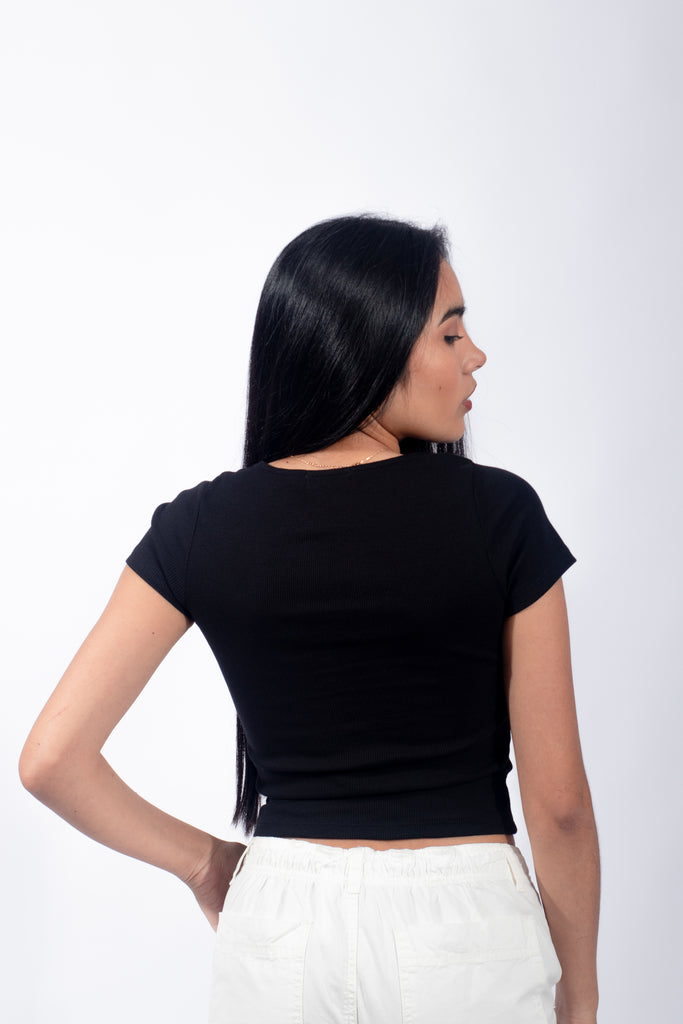 Polo básico de color negro con botones, destacando un estilo casual y minimalista para chicas jóvenes.