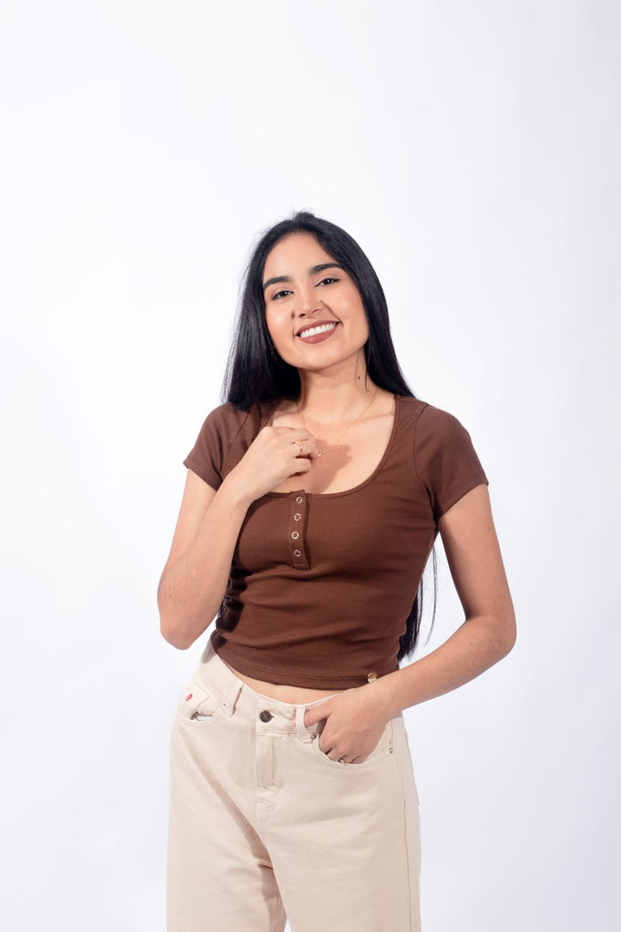Mujer joven llevando un polo básico con botones de color marrón, reflejando un temperamento casual y minimalista.
